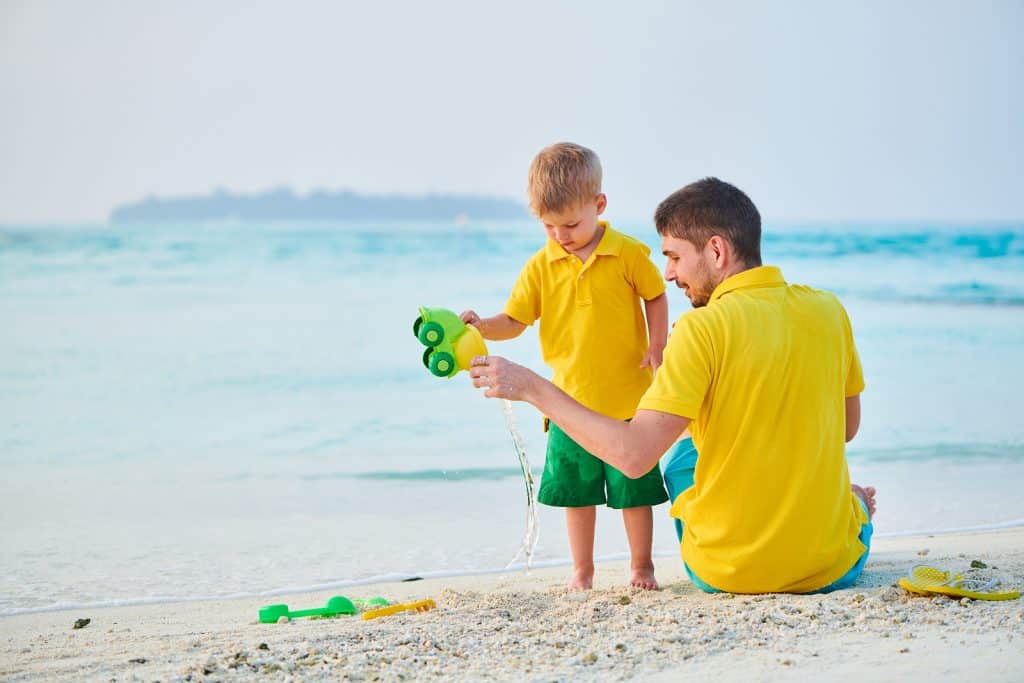 Three year old toddler boy on beach with father. by Krystal International Vacation Club